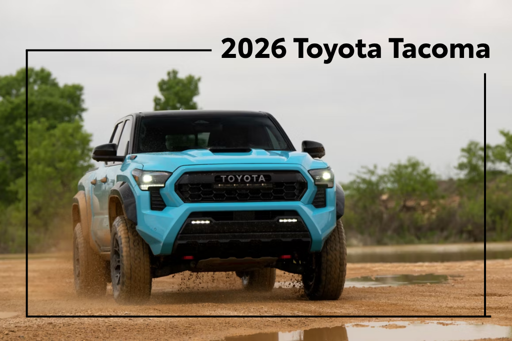 Blue 2026 Toyota Tacoma driving off-road on a dirt trail with rugged terrain in the background.