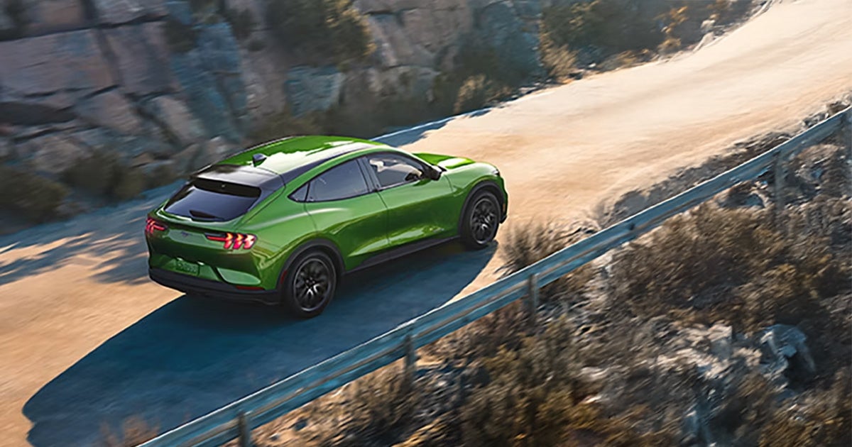 A green Ford Mach-E all electric SUV on the road.