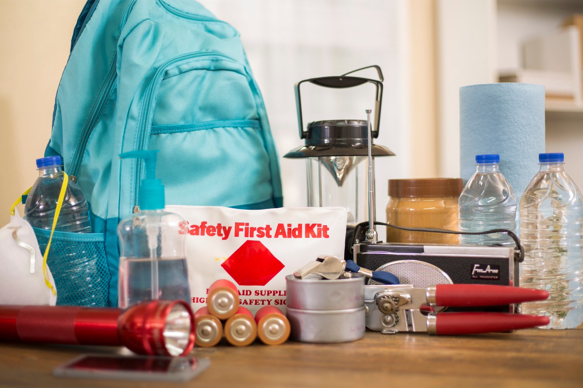 Emergency preparedness supplies. A large collection of supplies to be used in case of a natural disaster (hurricane, flood, earthquake, etc) including flashlight, backpack, batteries, water bottles, first aid kit, lantern, radio, can opener and mask. No People.