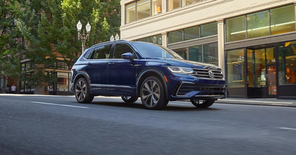 New 2024 Volkswagen Tiguan in atlantic blue metallic driving through a city street.