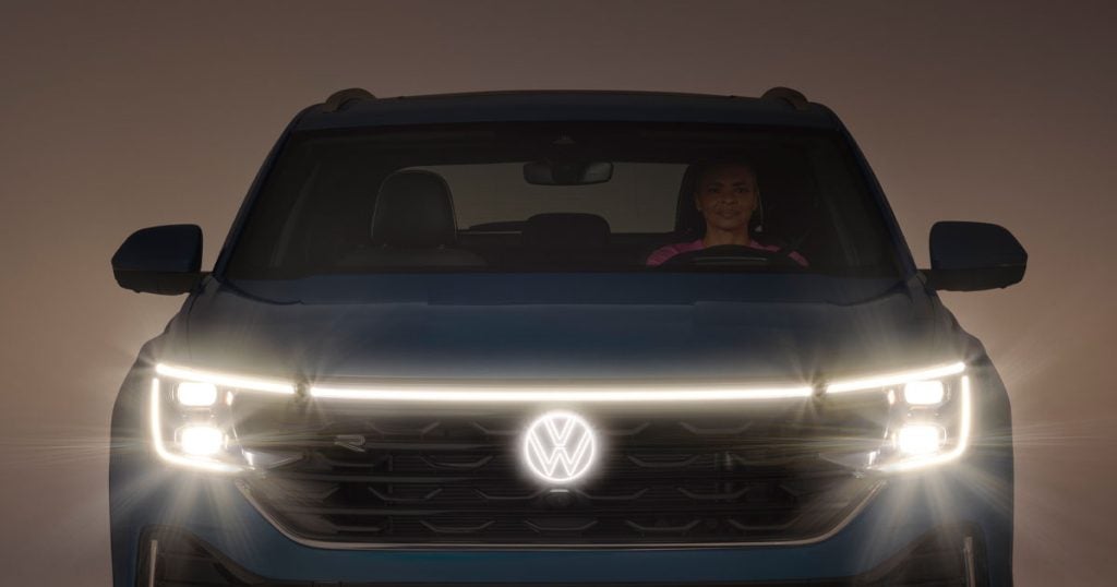 A Volkswagen Atlas in a dark room with the headlights shining bright.