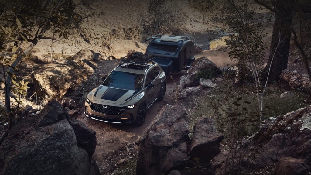Mazda CX-50 SUV towing a small camper on rocky off-road trail