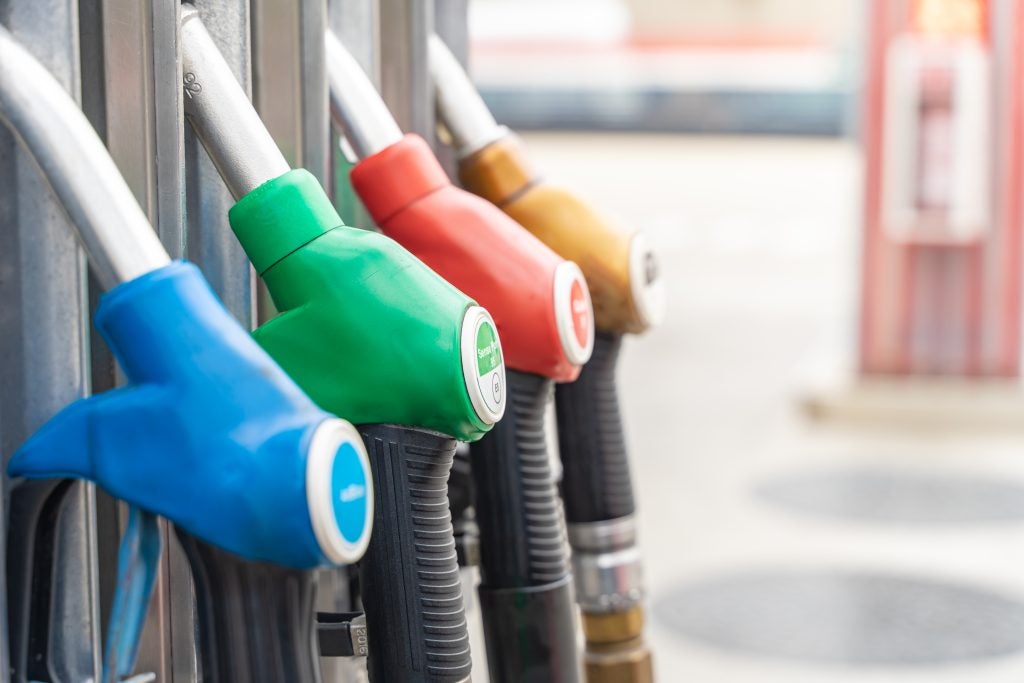 Color-coded fuel pump nozzles at a gas station close-up.