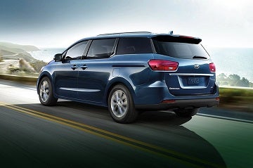 A Kia Sedona driving on the road.