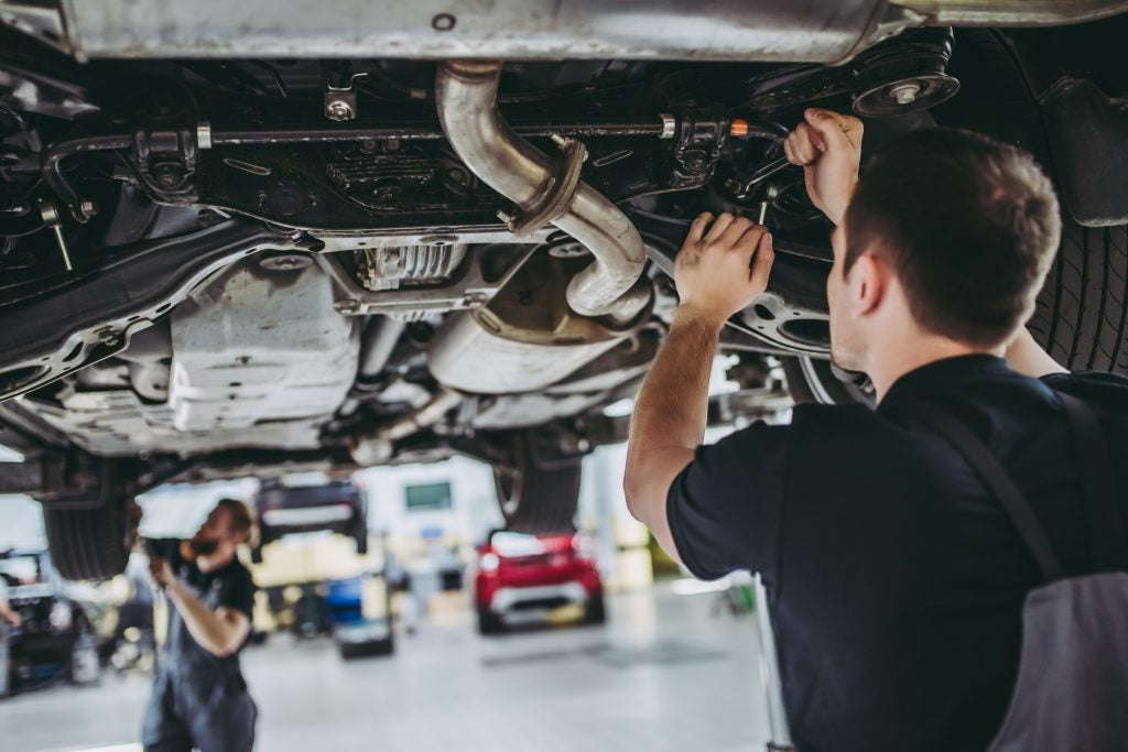 Mechanic working under a car in an auto repair shop.
