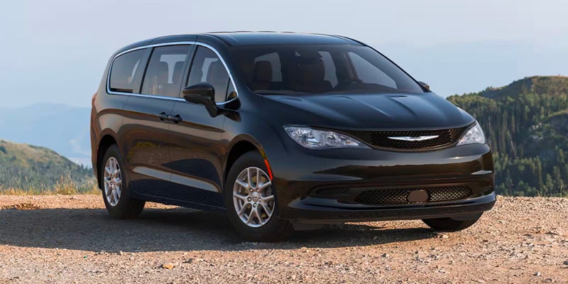 Chrysler Voyager minivan parked on a rugged terrain with scenic background.