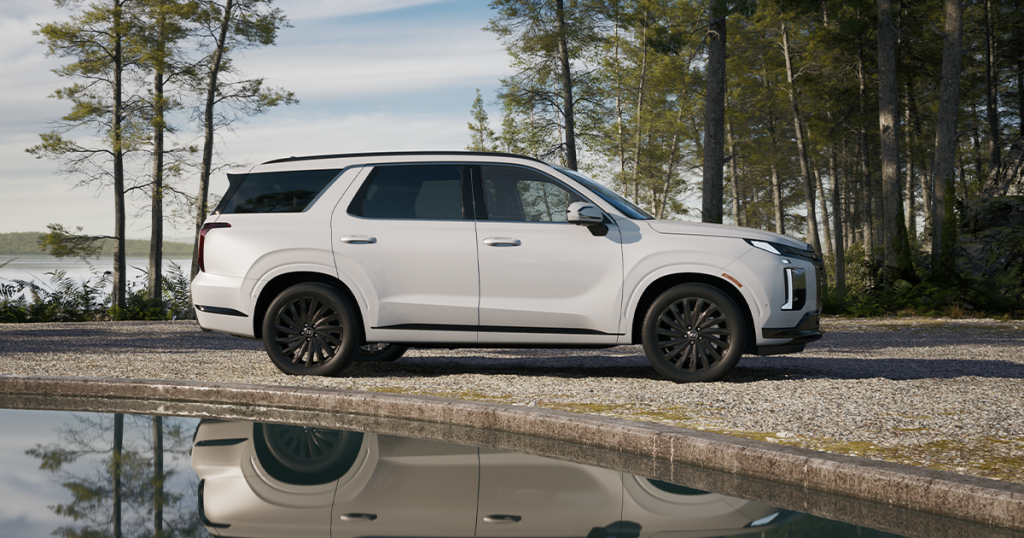 2024 Hyundai Palisade in the hyper white color parked outdoors by a lake.