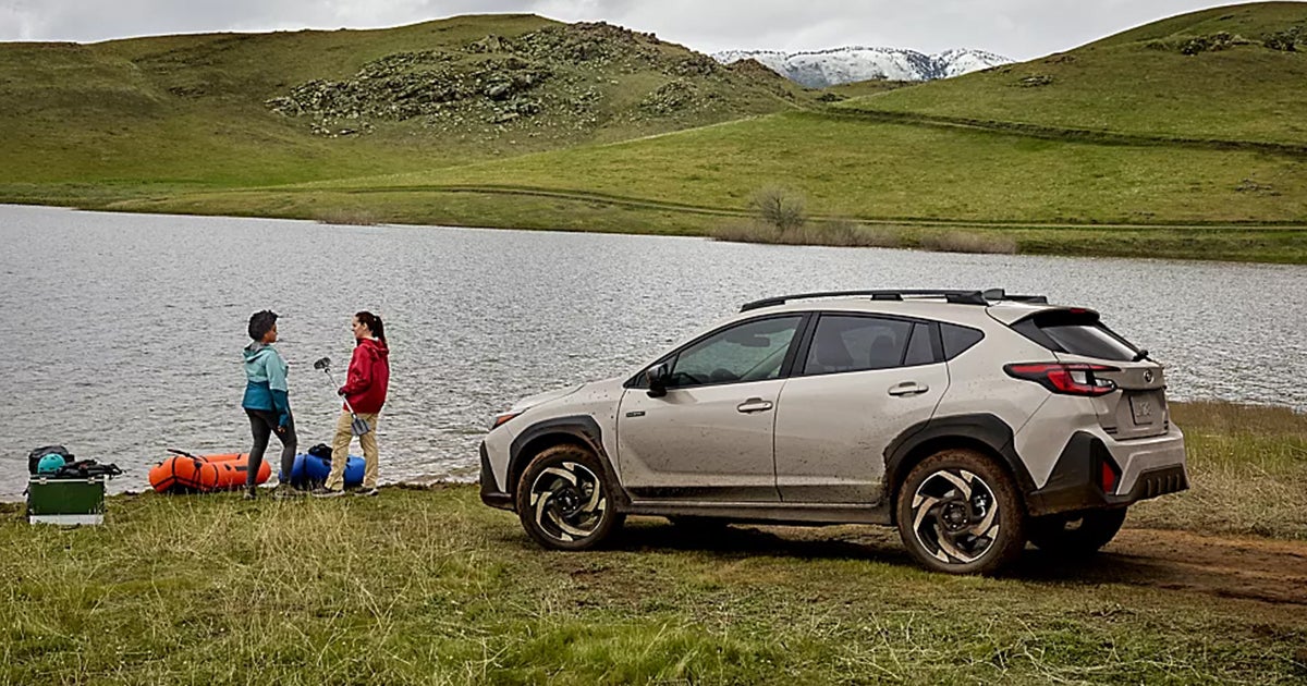 A white Subaru Crosstrek Hybrid parked by a lake.