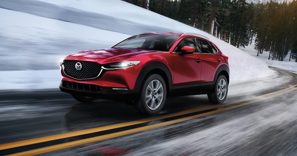 A Mazda SUV driving along a snowy road.