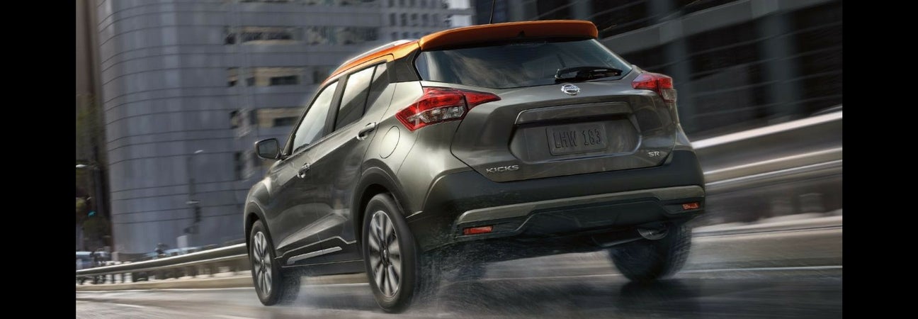 A 2018 Nissan Kicks driving away down a city street