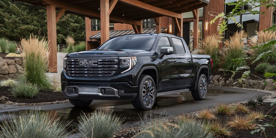 A black GMC Sierra 1500 parked in the driveway of a nice house.