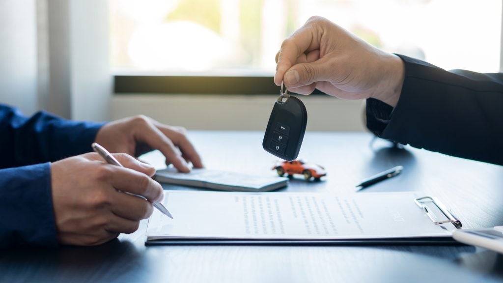 Agent giving keys to a customer who is signing a purchase agreement