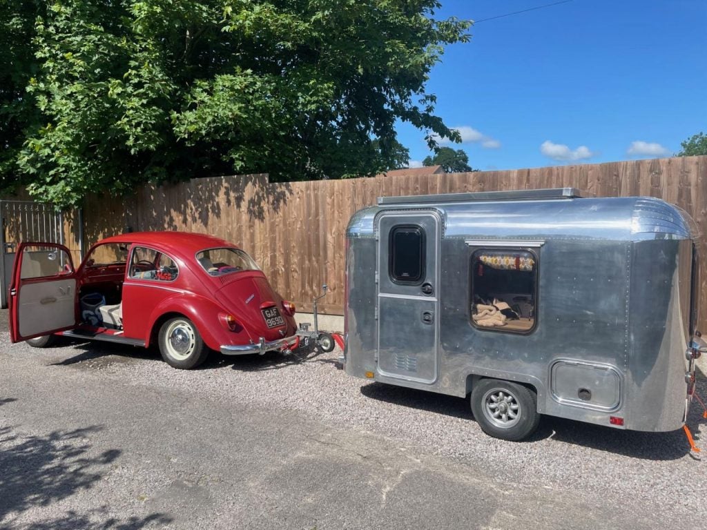 A Red Volkswagen Beetle Decisively Towing A Bluish Metal Trailer