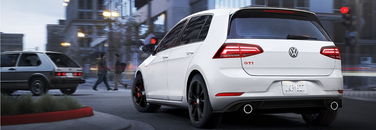 2019 Volkswagen Golf GTI in white with black rims maneuvering through a round-about