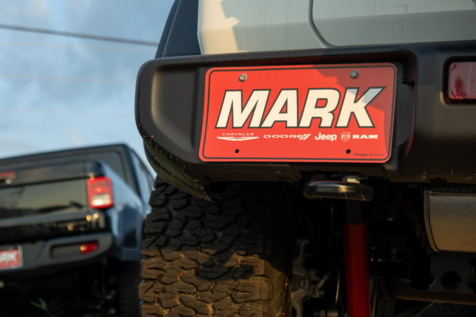 Extreme close-up of a Mark Dodge Chrysler Jeep Ram Lake Charles dealer license plate mounted on a Jeep's rear bumper.