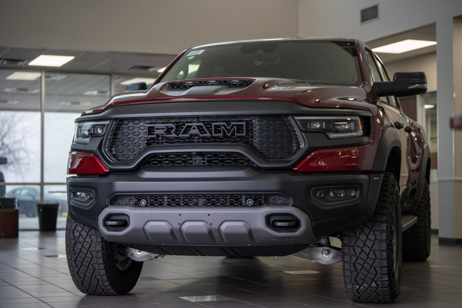 Front view of a dark red Ram TRX pickup truck displayed on the showroom floor inside the Mark Dodge dealership.