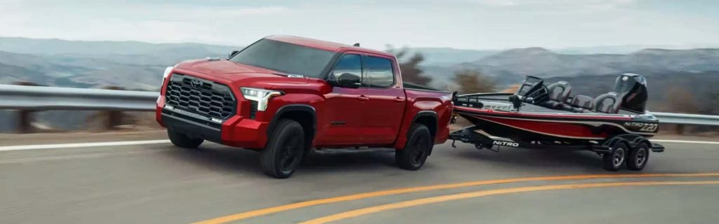 Red pickup truck towing a black and red boat on a trailer