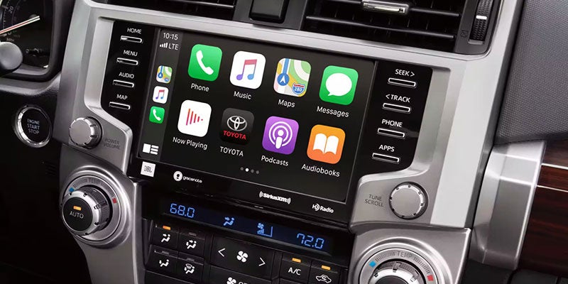 A car's dashboard infotainment system with a large touchscreen displaying apps like Phone, Music, Maps, and Messages.