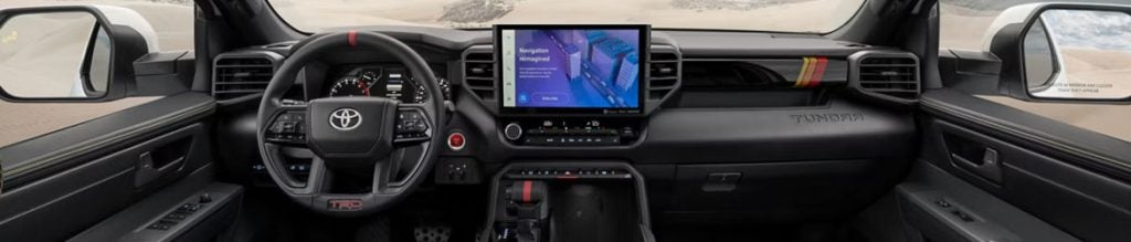 Interior view of a modern dark gray car with a large touchscreen displaying Navigation Reimagined.