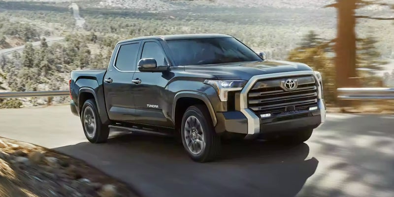A dark gray 2022 Toyota Tundra pickup truck driving on a paved winding mountain road.