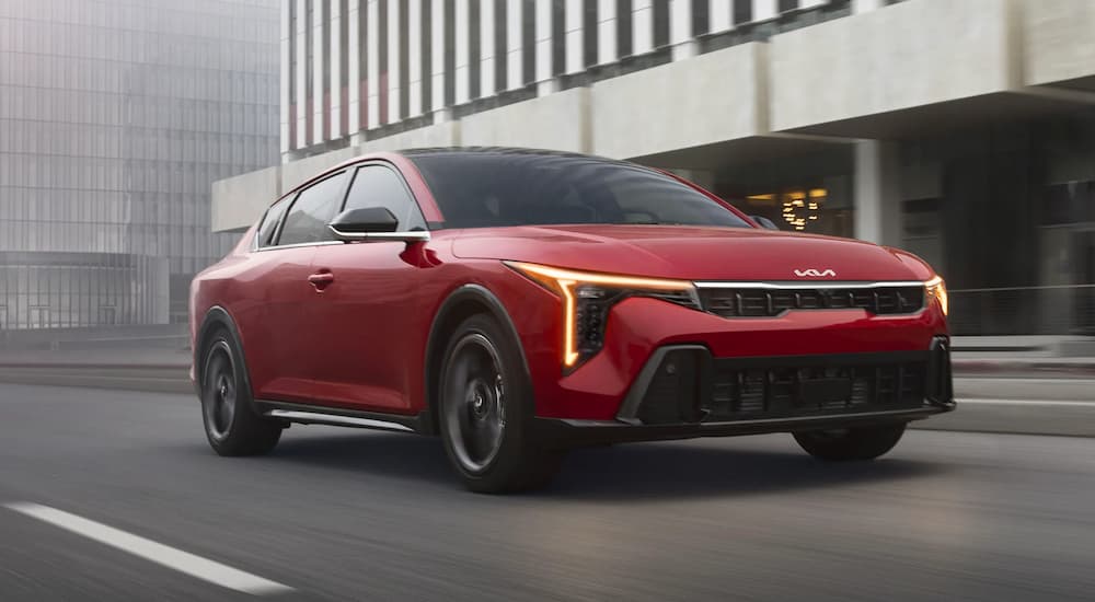 A red 2026 Kia K4 driving in a city