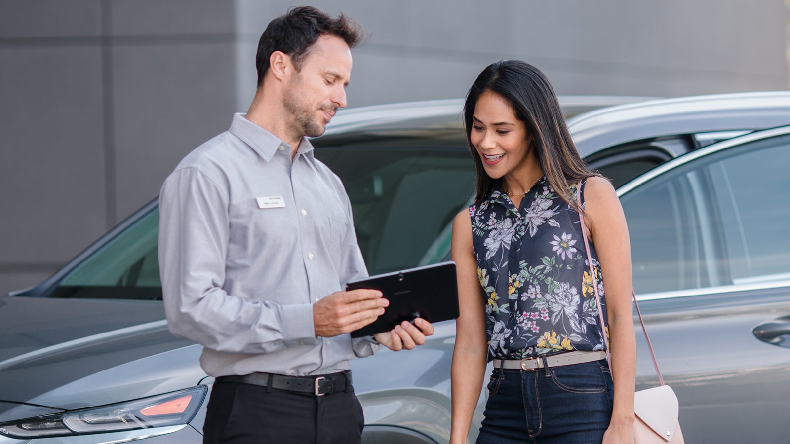 Hyundai technician reviewing service details with a customer beside her vehicle
