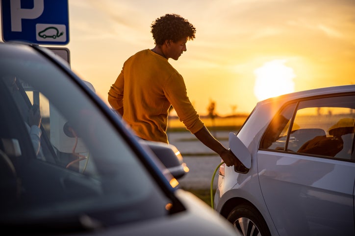 A man charging his electric car at a public charging station