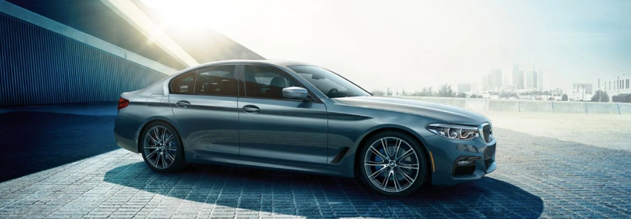 Silver 2019 BMW 5 series parked outside of a city.