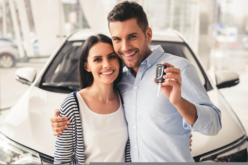 The Benefits of Buying a Vehicle Driver holding car keys next to a new vehicle