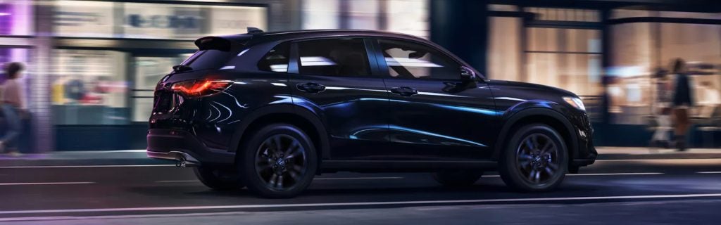 Black Honda HR-V driving through a city street at night, highlighting its sleek design and urban versatility.