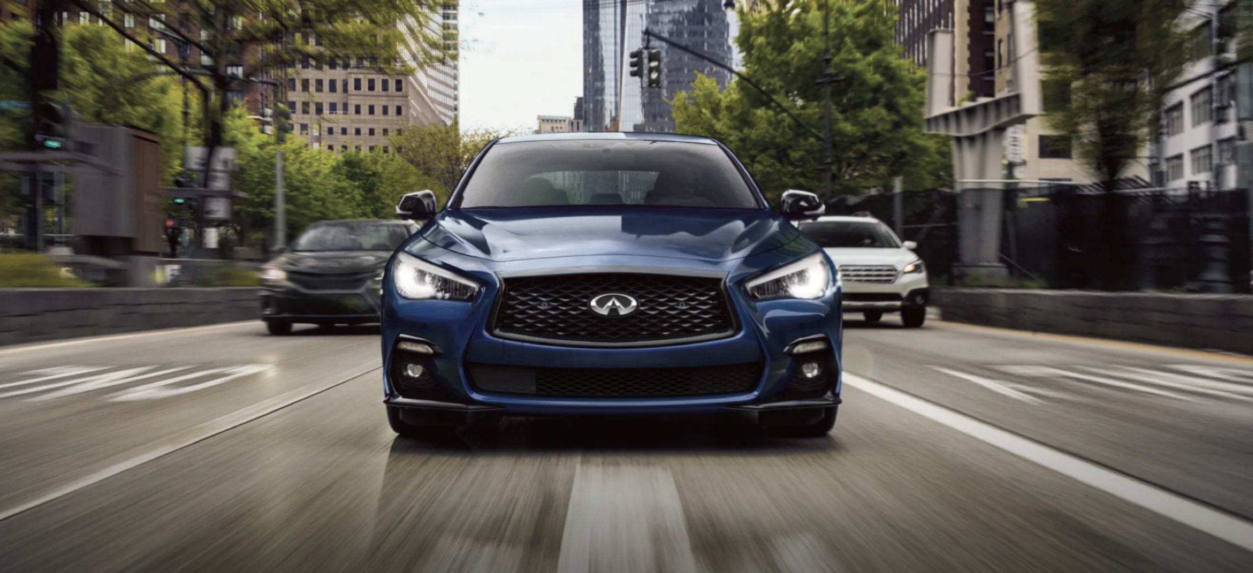 A blue 2021 Infiniti Q50 driving on the road