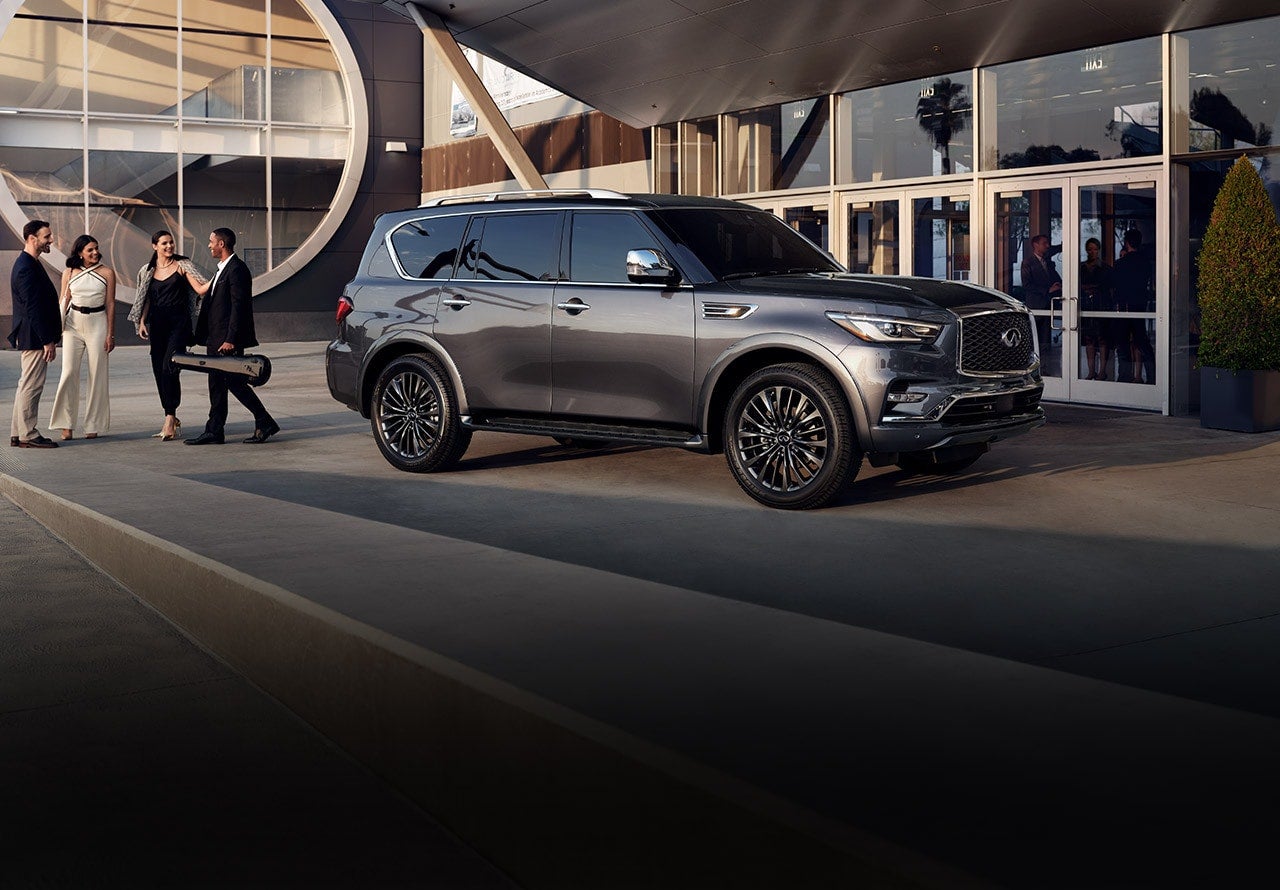 A 2022 Infiniti QX80 parked next to a building as passengers walk away towards their destination
