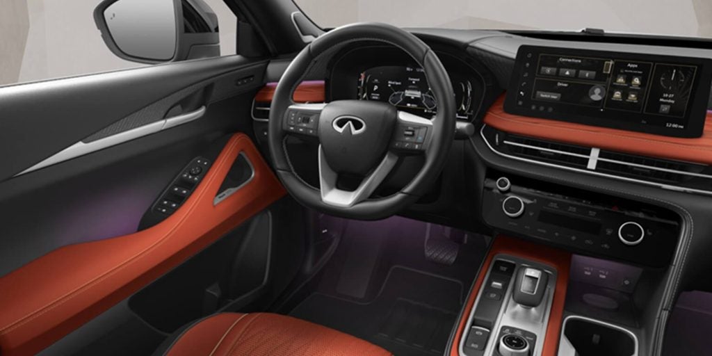 Interior view of an Infiniti SUV showing steering wheel, digital dashboard, and infotainment screen.