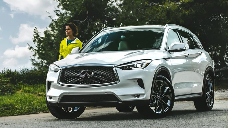 White Infiniti Q50 SUV parked outdoors near trees.