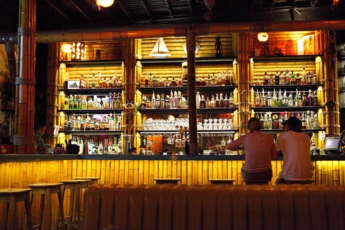 Two people sitting at a bar with bamboo