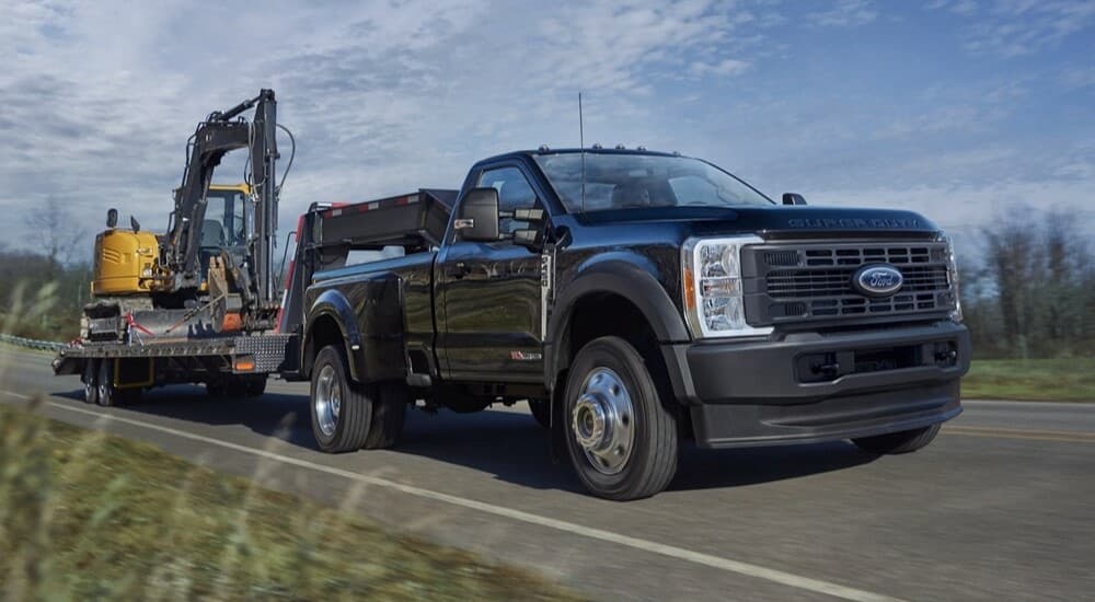 A black 2026 Ford F-450 towing a trailer to view work trucks for sale.