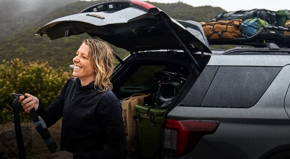 A person standing near an open tailgate of a silver 2026 Ford Explorer.