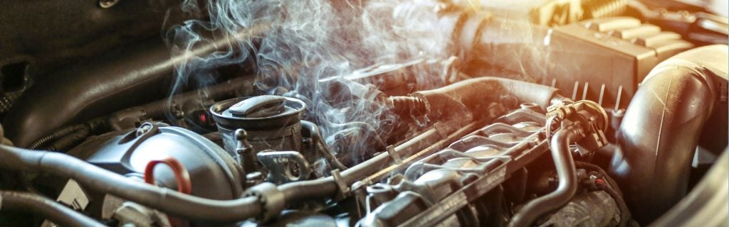 Smoke and steam rising from an overheating car engine.