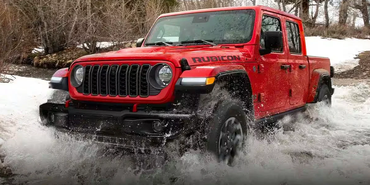 A 2024 Jeep Gladiator driving through the rough waters of a river