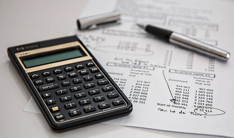 A handful of investing tools such as a calculator sitting on a desktop