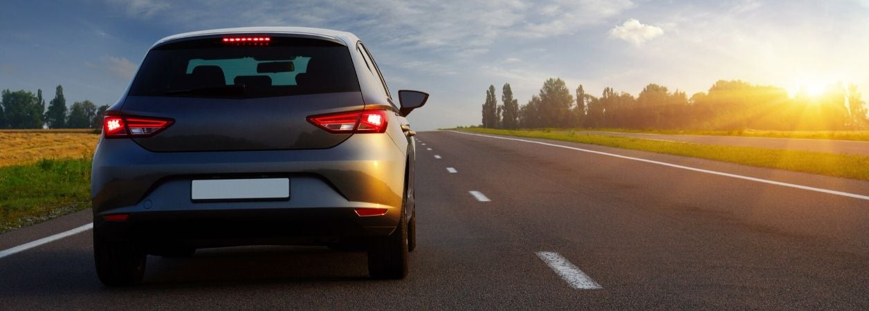 car driving down highway at sunrise