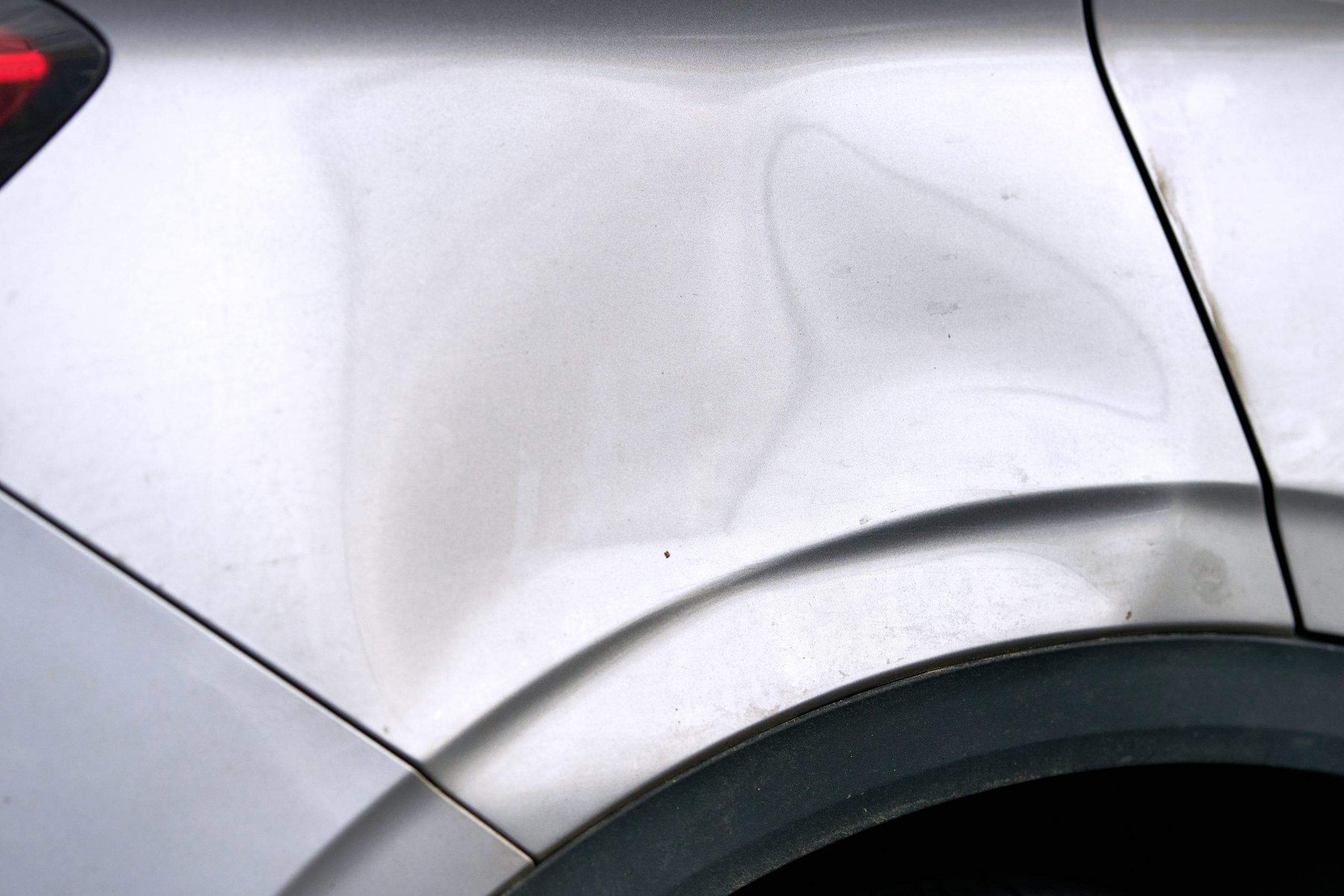 Dented,,Scratched,Car,Body,Near,Rear,Wheel,Arch,Showing,Paint