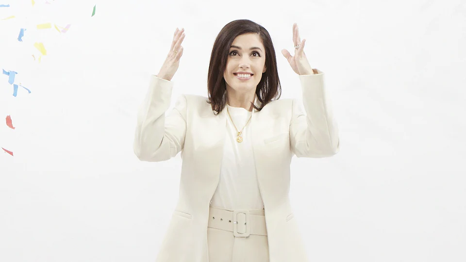 An animation showing Jennifer Widrick dressed in white and standing in front of a white background while she throws handfuls of colorful confetti into the air.