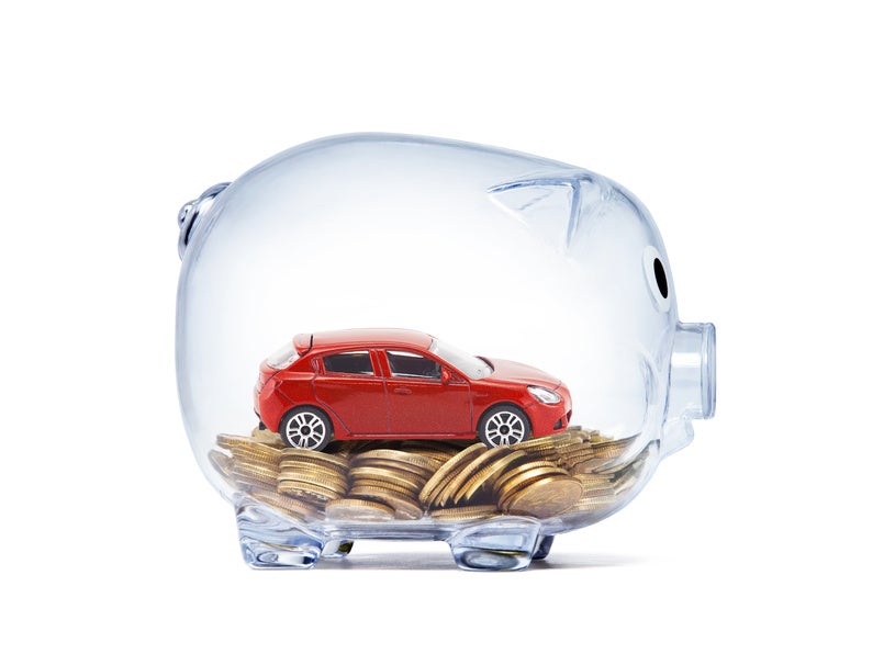 Red car on money inside transparent piggy bank with clipping path