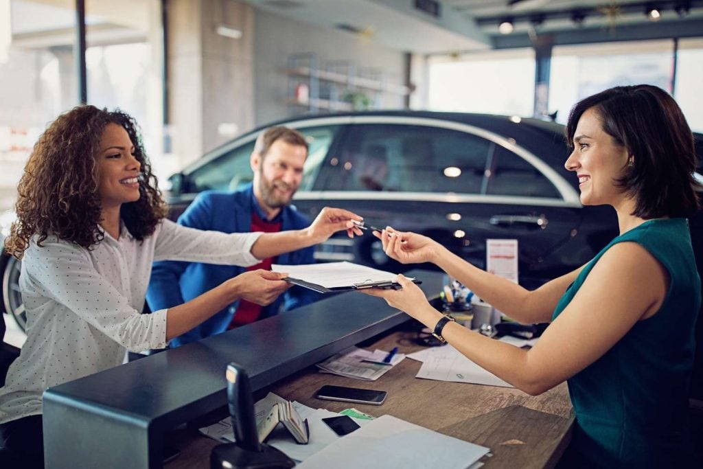 A woman being handed keys in a dealership after deciding if she was leasing or financing