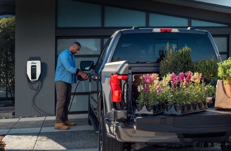 Man Charging a 2023 Ford F-150 Lightning in a Driveway