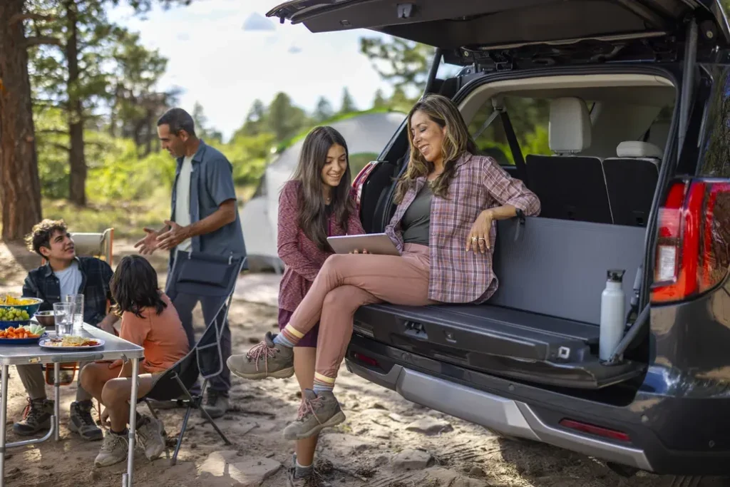 Ford Customer Using Their Ford Expedition's Split Tailgate and Backrest as a Seat on a Camping Trip with Their Family