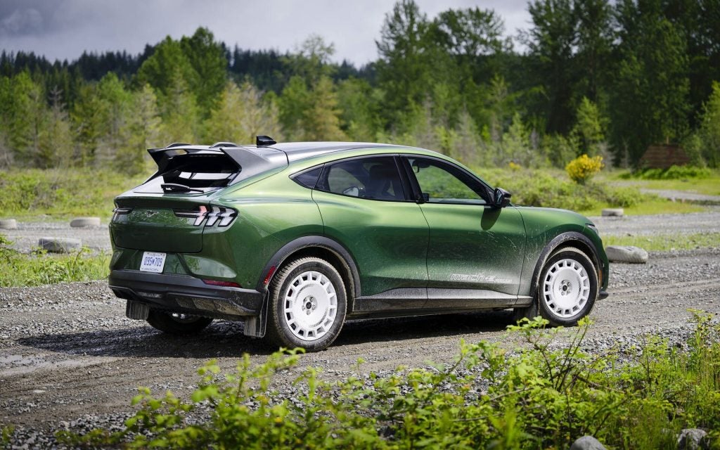 A Gorgeous Dark Green 2024 Ford Mustang Driving On The Track