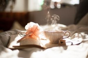 Small blush tea cup resting on a journal with a pen on the opposite page.