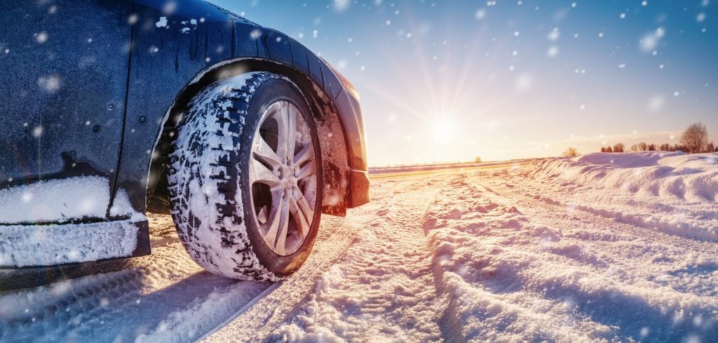 A vehicle driving over a snowy road while it's snowing.